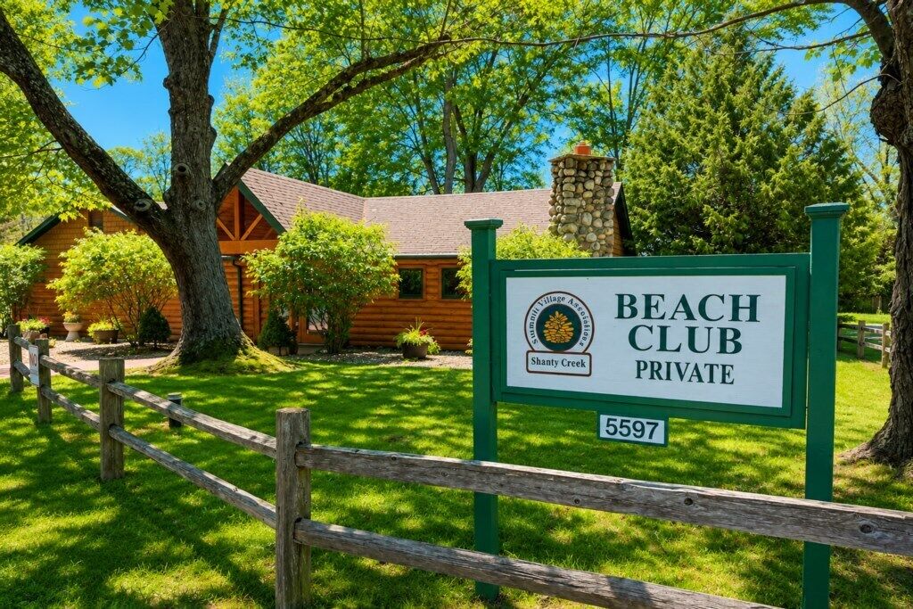 A private beach club sign with a lodge in the background.