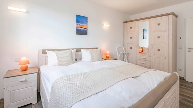 Une chambre à coucher avec un grand lit, des tables de chevet, une armoire et un tableau au mur.