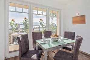 A dining area with a glass table, four chairs, and a view of the outdoors.