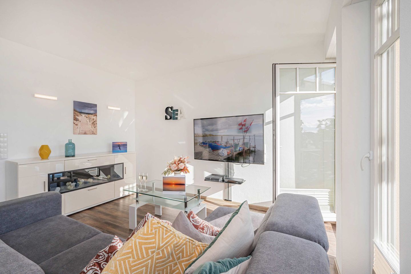 Un salon moderne avec une table basse en verre, un téléviseur à écran plat et un canapé.