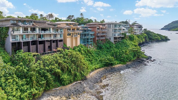 A coastal hotel with multiple balconies, lush greenery, and a view of the sea. - Oceanview Kauai Retreat | Balcony & Beach Access (Lihue)