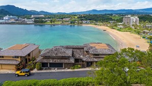 A coastal area with a beach, a yacht, and residential buildings. - Oceanview Kauai Retreat | Balcony & Beach Access (Lihue)