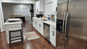 Cozinha moderna com armários brancos, eletrodomésticos de aço inoxidável e piso de madeira.