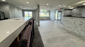 A spacious indoor area with a long counter, multiple seating options, and a stone accent wall. - Best Western Red River Lodge Fargo ND (Fargo)