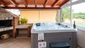 Jacuzzi exterior con señal de precaución, chimenea de ladrillo y techo de madera.