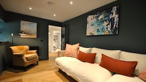 Ein modernes Wohnzimmer mit einer Couch, einem Sessel und einem Bild an der Wand.