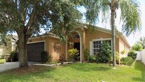 A single-story house with a garage, a well-maintained lawn, and mature trees.