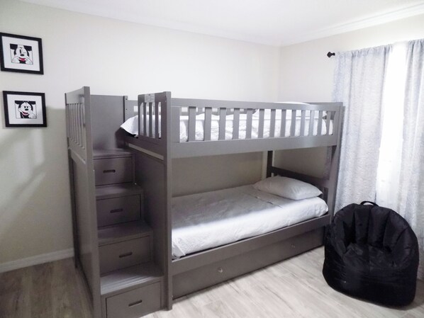 A bunk bed with a ladder, a small desk, and a black bag.