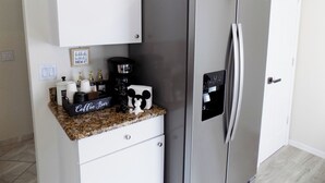 A kitchen with a stainless steel refrigerator, a coffee maker, and a coffee bar sign.