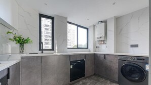 A modern kitchen with a dishwasher, washing machine, and a large window providing a view of the city. - Eastern Hub - Brand New Apartment, Walk to People Square, Bund, Yuyuan Garden (Shanghai,)
