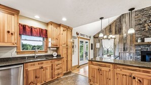 A spacious kitchen with wooden cabinets, granite countertops, and a stone backsplash.