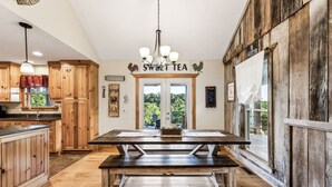 A rustic kitchen with wooden cabinets, a central wooden table, and a sign reading "Sweet Tea".
