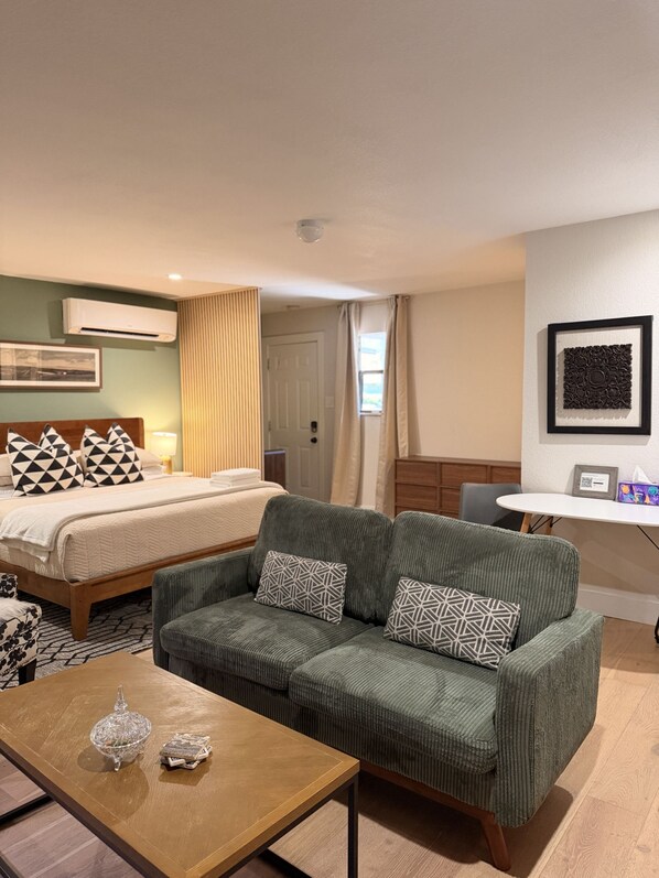 A hotel room with a bed, a sofa, a coffee table, and a desk.