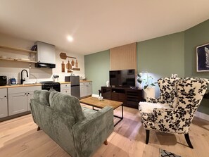 Een moderne woonkamer met een bank, fauteuil en een flatscreen televisie.
