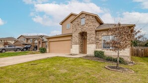 A residential house with a garage, a driveway, and a well-maintained lawn. - 4BR King and Queens 2 living spaces | Location (Austin)