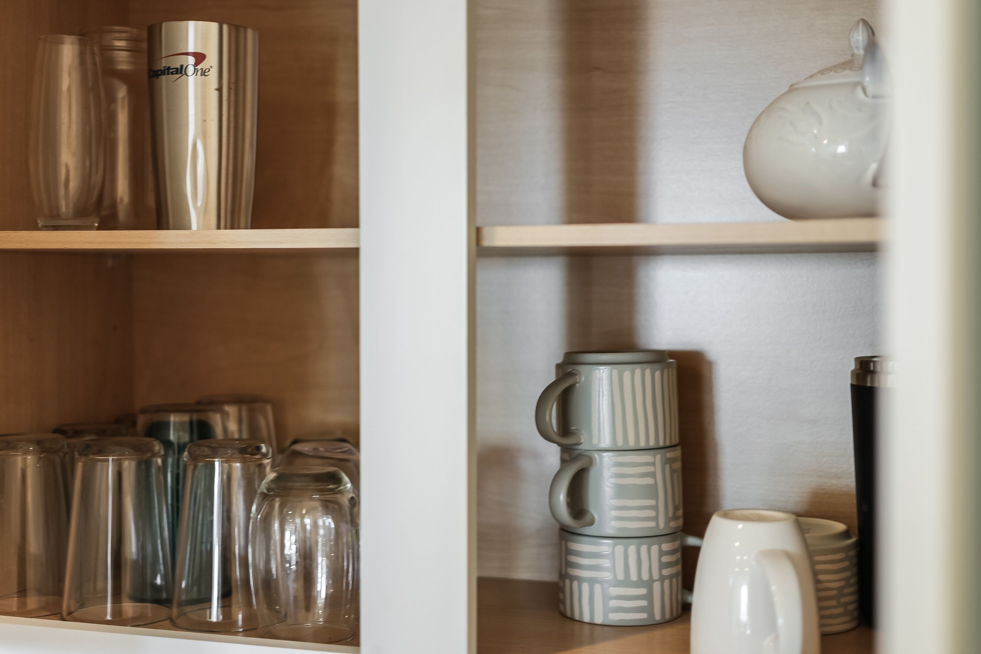 A shelf with various glassware and ceramic mugs.