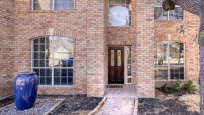 A two-story brick building with large windows, a central door, and a blue pot in the foreground. - 5BR Cedar Park | Near HEB Center + Private Yard (Cedar Park)
