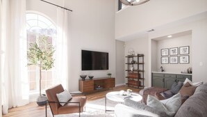 A modern living room with a sofa, armchair, coffee table, TV, bookshelf, and a potted plant. - 5BR Cedar Park | Near HEB Center + Private Yard (Cedar Park)
