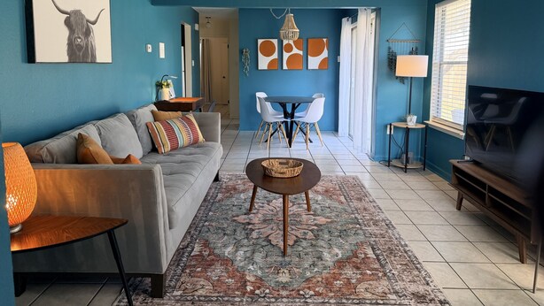 Een woonkamer met een bank, salontafel, televisie en een eethoek met stoelen en een tafel.