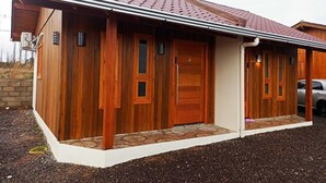 A two-story wooden house with a red-tiled roof, a covered porch, and a driveway. - Aconchego da Serra Geminados (São Joaquim)