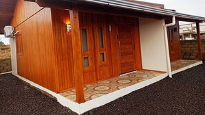 A modern building with a wooden facade, a covered entrance, and a tiled entrance area. - Aconchego da Serra Geminados (São Joaquim)