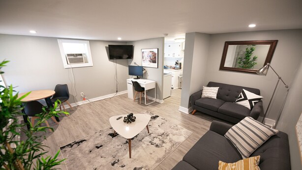 A modern living room with a sofa, a coffee table, and a TV. There is a dining area with a table and chairs.