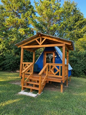 A wooden playhouse with a blue roof and a ramp leading up to the entrance. - Cozy Nature A-frame: AC, Heating, Electricity in Coldsprings (Coldspring)