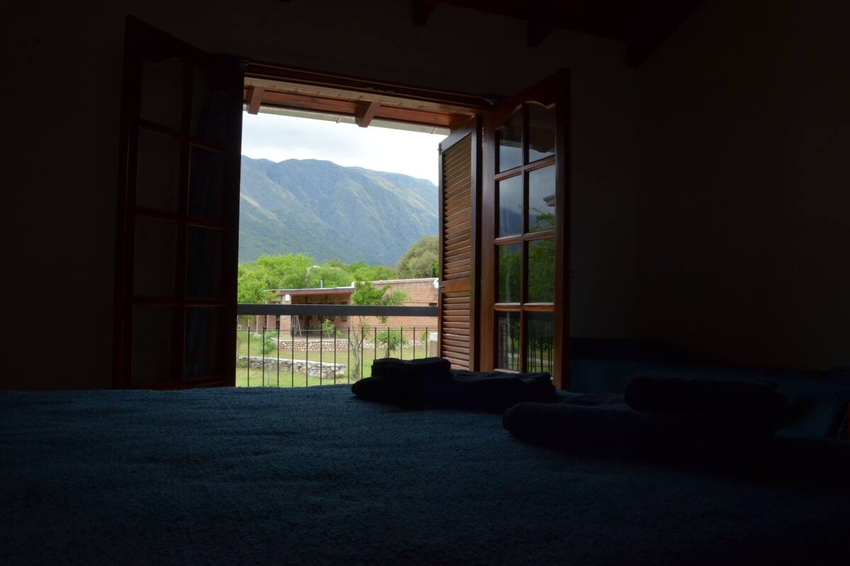 Una habitación con cama, ventana y vistas a las montañas.