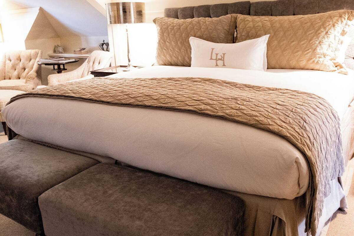 A neatly arranged bedroom with a large bed, a bedside table, and a chair.