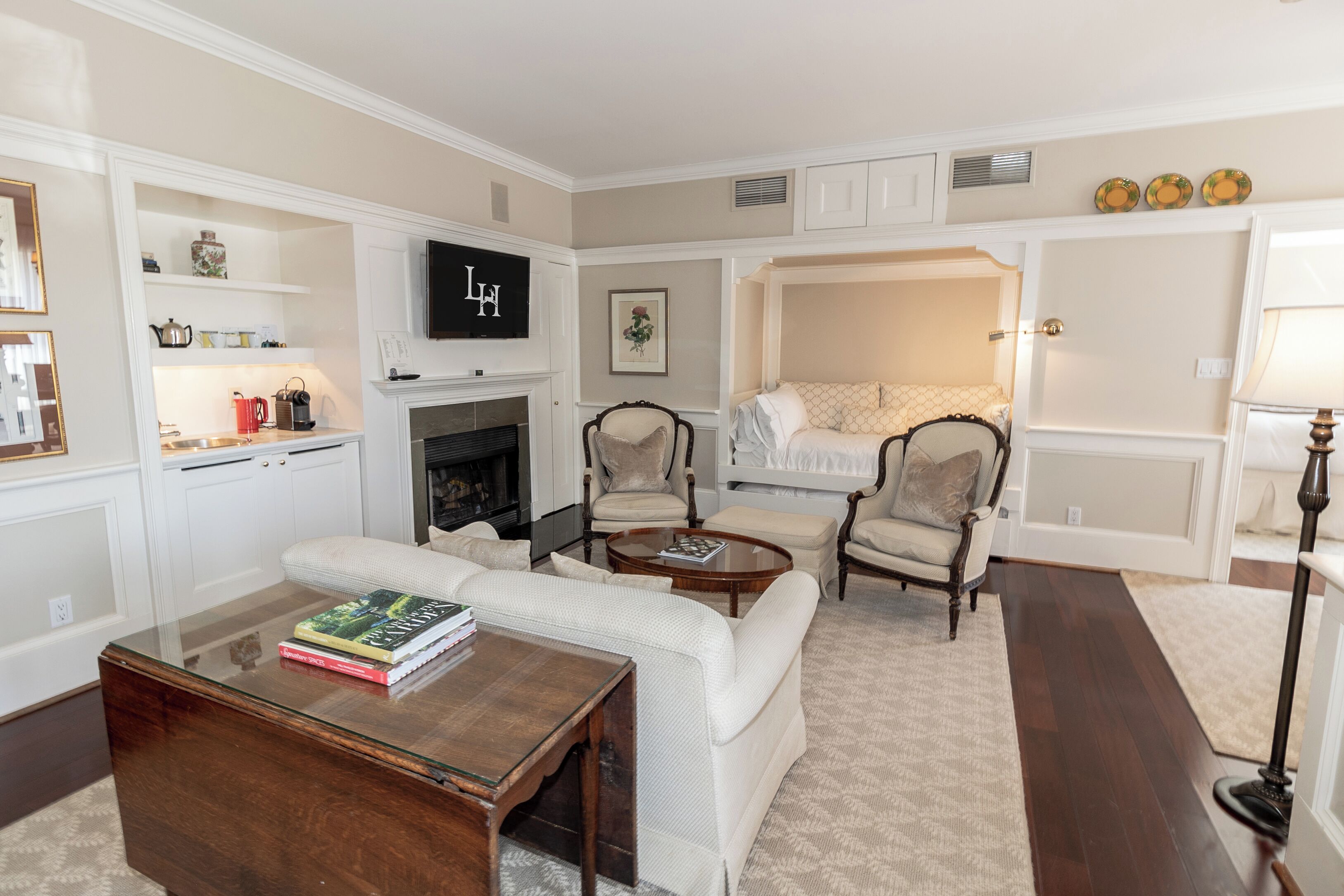 A living room with a fireplace, a television, and a bed with a canopy.