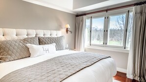 A bedroom with a large bed, a headboard, a nightstand, a lamp, and a window with curtains. - Langdon Hall Country House Hotel & Spa (Cambridge)