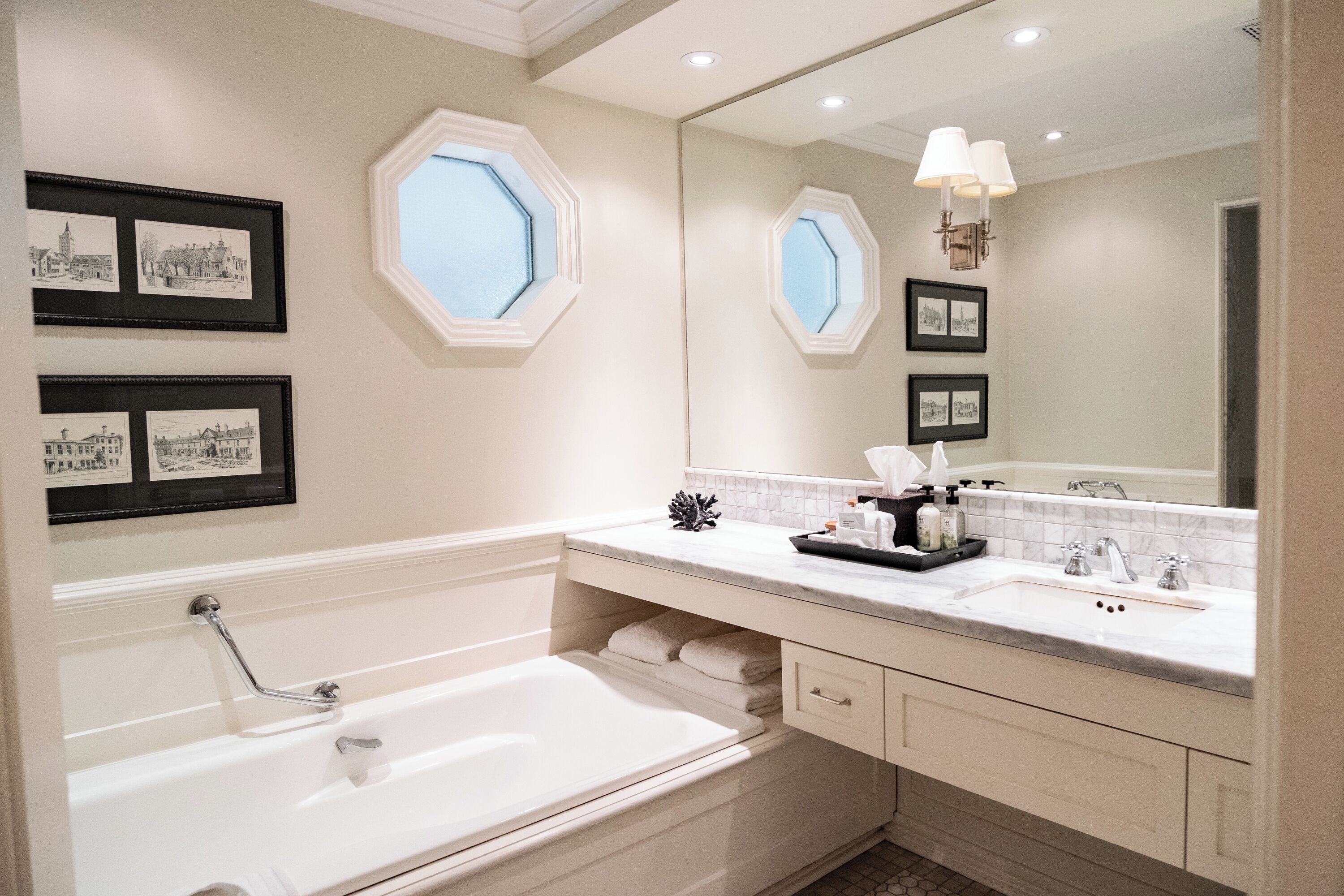 A modern bathroom with a large bathtub, a vanity with a sink, and framed pictures on the wall.