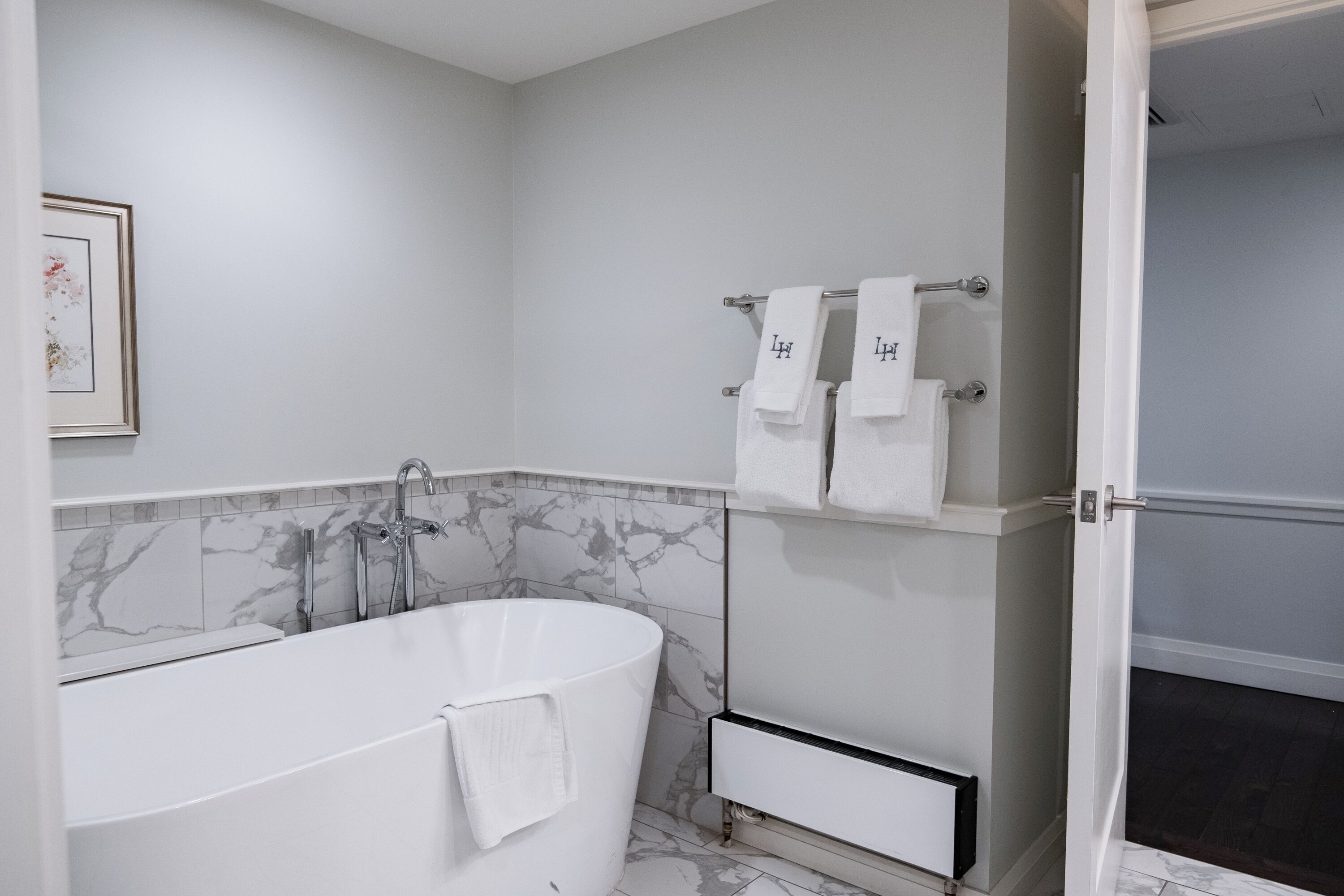 Une salle de bain moderne avec une baignoire sur pieds, un porte-serviettes avec deux serviettes et un tableau encadré au mur.