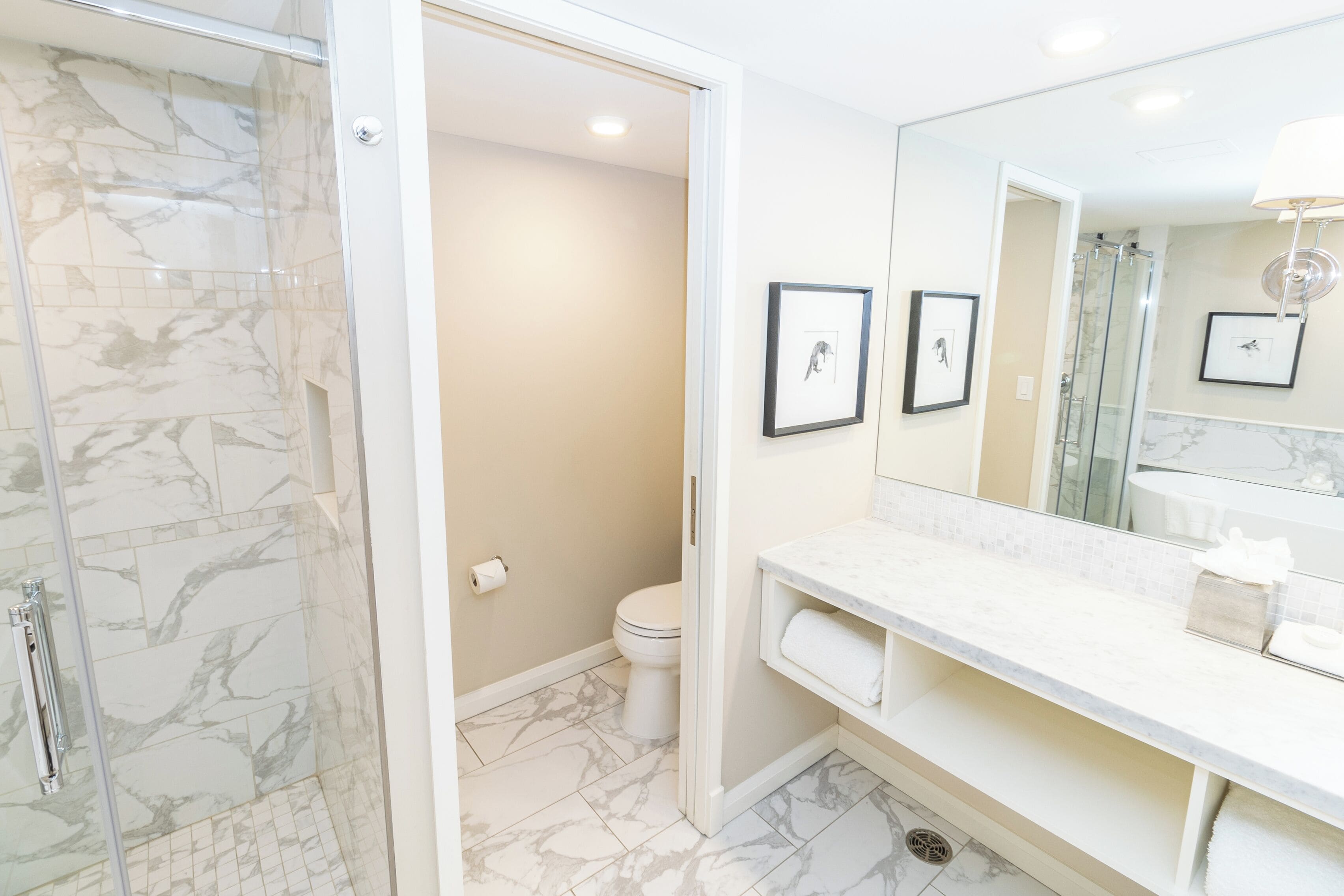 Un baño con cabina de ducha de vidrio, inodoro y tocador con espejo.