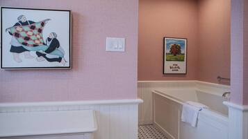 A bathroom with a white vanity, a bathtub, and two framed pictures on the wall.