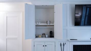 Una habitación con una puerta blanca, un armario blanco con estantes abiertos y una chimenea.