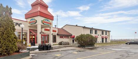 A motel with a red-roofed building, a KFC restaurant, and a sign for a restaurant.