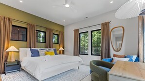A modern bedroom with a large bed, bedside lamps, a desk, and a chair. - Rooftop Deck, Hot Tub, Speakeasy, Columbus Luxury (Columbus)