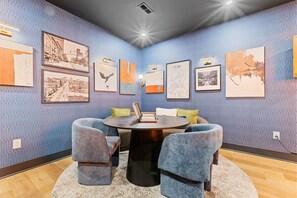 A conference room with a round table, four chairs, and a coffee table. The walls are adorned with framed artwork, and there is a ceiling light fixture. - Rooftop Deck, Hot Tub, Speakeasy, Columbus Luxury (Columbus)