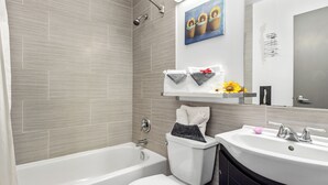 Een moderne badkamer met bad, toilet en wastafel. Er liggen handdoeken op de wastafel en staat een klein plantje.