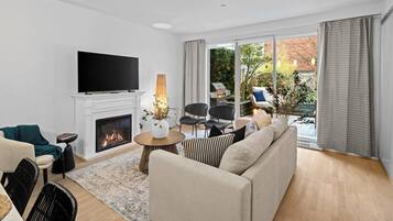 A modern living room with a fireplace, a flat-screen TV, and a large window with curtains.
