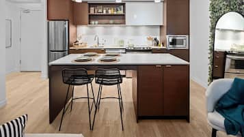 A modern kitchen with a central island, bar stools, a refrigerator, microwave, and a stove.