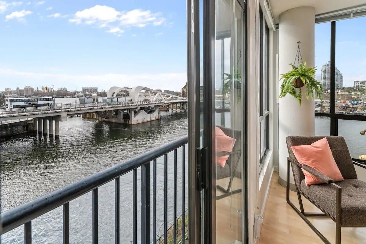 Un balcon offrant une vue sur une rivière, un pont et des bâtiments situés de l’autre côté.