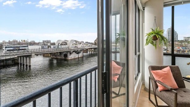 A balcony with a view of a river, a bridge, and buildings across the water. - Waterfront Stay with Balcony and BBQ (Victoria Central British Columbia Provincial Government)