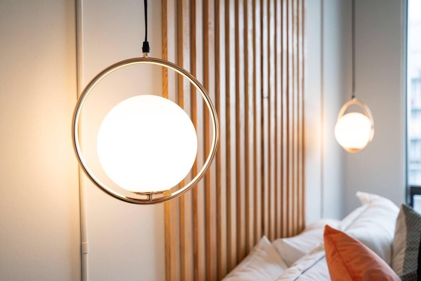 A modern bedroom with a bed, pillows, and a wall with vertical wooden slats.