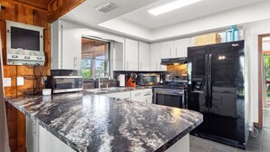 Una cocina moderna con encimeras de granito, electrodomésticos de acero inoxidable y armarios de madera.