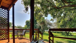 Una terraza de madera al aire libre con una mesa, sillas, una botella de vino y una copa.
