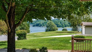 A residential property with a deck, a lawn, and a view of a lake.
