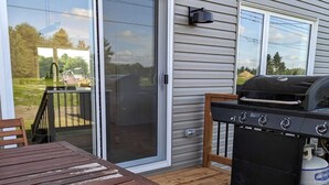 Une terrasse en bois avec un barbecue et une table.