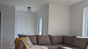 Un salon moderne avec une table basse en bois, un canapé d’angle beige et une armoire blanche.